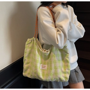 Détail du sac cabas à carreaux verts montrant la texture toile et l'étiquette colorée