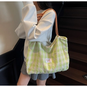 Detail of green checkerboard canvas tote with woven texture and orange rope handle