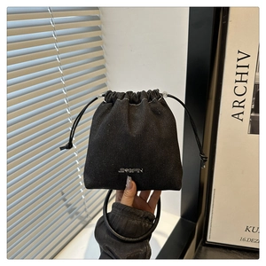 Détail du mini sac seau en denim noir avec logo argenté et poignée circulaire élégante