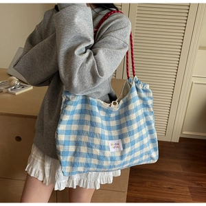 Detail of blue gingham tote bag with red rope straps and metal magnetic clasp closure