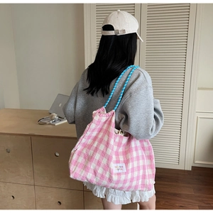 Pink checkered canvas tote bag with thick rope straps shown in a lifestyle setting
