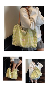Close-up of green checkerboard canvas tote with orange drawstring handles and label