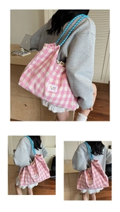 Close-up of pink checkered canvas tote bag with blue rope handles and woven logo detail