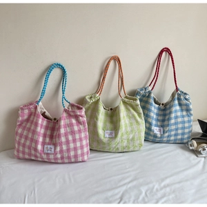 Close-up of pink, green and blue plaid tote bags with drawstring rope handles