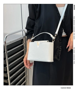 Detailed close-up of white luxury tote featuring crocodile texture and silver V-shaped buckle