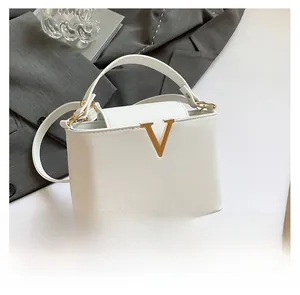 Close-up of white lychee leather handbag with elegant gold V-shaped metal hardware