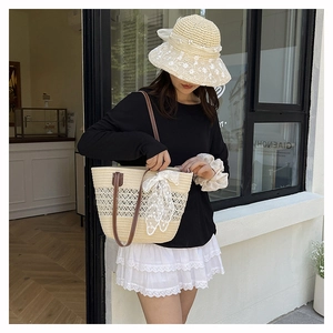 Close-up of woven straw tote bag and sun hat featuring white lace bow and embroidery