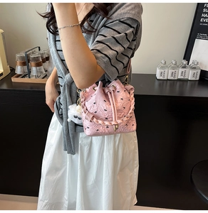 Detail of pink bucket bag with clover embossing, black bow print and fluffy charm