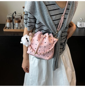 Detail of pink bucket bag with black bow prints and a soft plush pendant charm