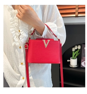 Detail of red PU leather bucket bag featuring a gold V-shaped metal buckle and handle