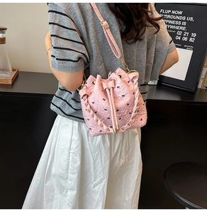 Detail of pink bow-patterned bucket bag with drawstring closure and pleated top edges