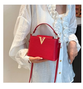 Sac à main rouge texture crocodile avec boucle V dorée sur fond blanc