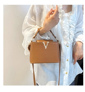 Détail du sac seau en cuir marron avec fermoir en V argenté et poignée élégante