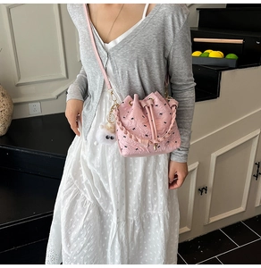 Detail of pink bucket bag featuring black mini bows and a white plush charm accessory