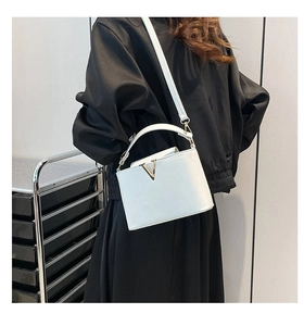 Close-up of white lychee leather handbag with signature gold V-shaped buckle hardware