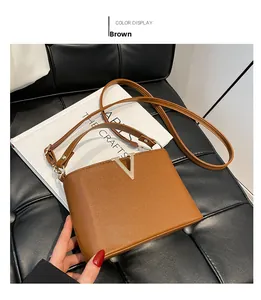 Macro detail of brown litchi pattern leather bag with golden V-shaped metal buckle