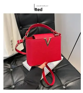 Detail of red leather bucket bag featuring a golden V-logo on a black quilted background
