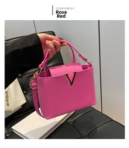 Detail of rose red luxury textured handbag with gold V-shape buckle and top handle