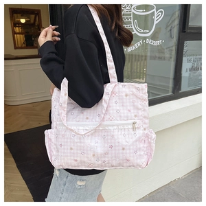 Close-up of pink plaid tote bag featuring star prints, lace trim, and front zipper pocket