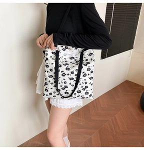 Close-up of a floral canvas tote bag with black straps and secure metal button closure