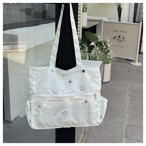 Close-up of green checkerboard tote bag with star patterns and white zipper pocket