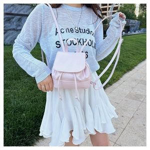 Pink PU leather mini backpack with drawstring and magnetic closure shown as a crossbody bag