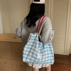 Blue and white checkered canvas tote bag with red rope straps and a woven patch label