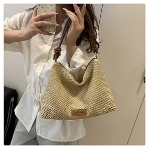 Detail of hand-woven straw tote with brown leather handles and decorative knots