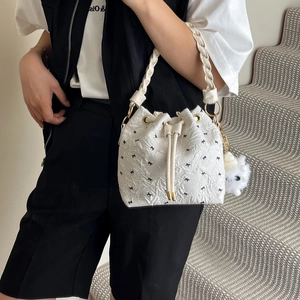 White pleated bucket bag with black bow print, woven handle and plush doll charm