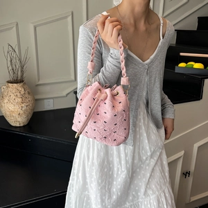 Pink drawstring bucket bag with black bow patterns and braided top handle for women