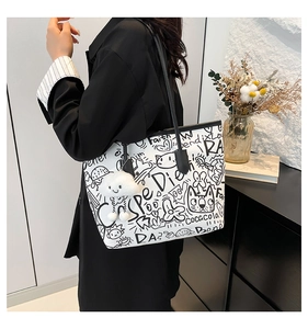 Detail of white graffiti canvas tote bag with black handles and plush cloud charm on model