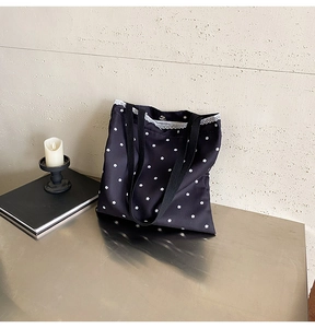 Detail of black canvas tote bag featuring white floral patterns and delicate lace trim edge