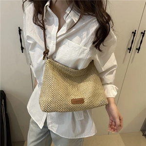 Chic beige woven straw shoulder bag with brown leather straps and fashion label detail