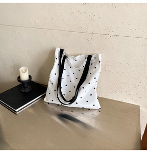 Detailed shot of white canvas bag with black star prints and secure metal snap closure