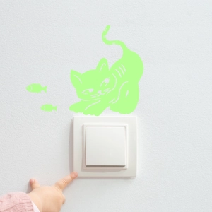 Luminous green kitten and fish wall stickers glowing on a white light switch