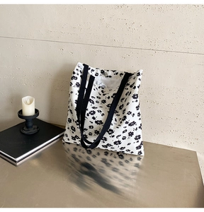 Detail of floral canvas tote bag showing metal snap button closure and black floral print