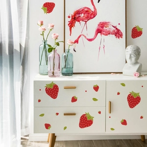 Detailed view of red strawberry wall decals applied on a minimalist white cabinet surface