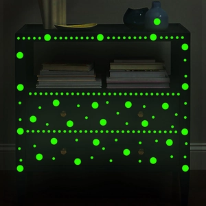 Luminous green dot stickers glowing on dark bedside furniture for wall decoration