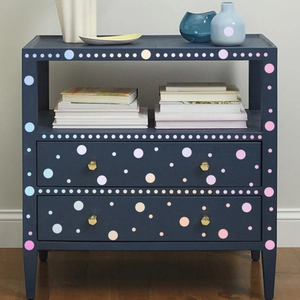 Close-up of colorful round dot decals on a modern dark blue wooden cabinet with gold handles