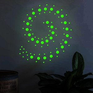 Luminous wall stickers with glowing dots forming a spiral galaxy in a dark bedroom setting