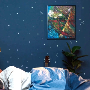 Detailed view of colorful luminous polka dot wall stickers glowing in a dark bedroom