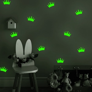 Luminous green crown wall stickers glowing in a dark room setting with decorative furniture