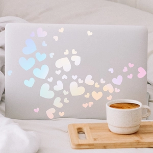 Close-up of pastel macaron heart stickers on a laptop in a cozy home office setting