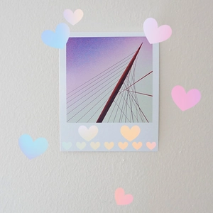 Luminous heart and dot wall stickers decorating a Polaroid print on a textured surface