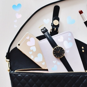 Flat lay of quilted shoulder bag with accessories including phone, watch, and lipstick