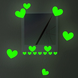 Luminous green heart wall stickers in various sizes glowing in a dark bedroom