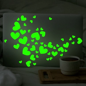 Detailed view of luminous green heart wall stickers glowing on a laptop in dark setting