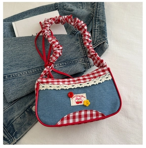 Detalle del bolso de hombro vaquero azul con volantes de cuadros rojos y cerezas