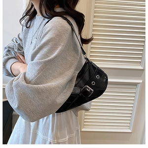 Close-up of a glossy black patent leather underarm bag with a bold silver metal buckle