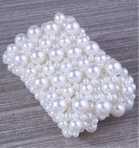 Detailed view of handmade wide elastic bracelet with multi-sized white pearls on wood